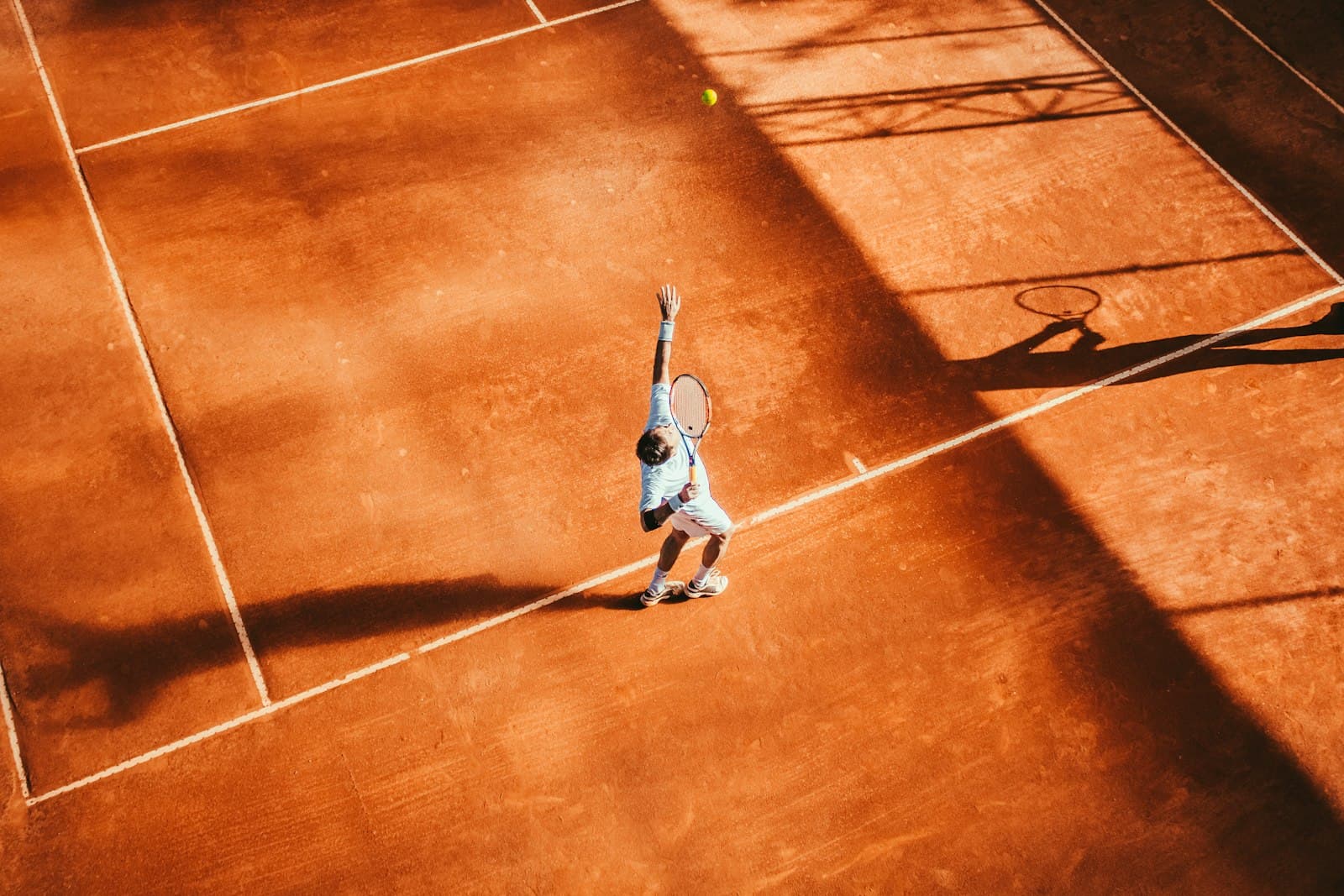 Aerial view of a sunlit clay tennis court